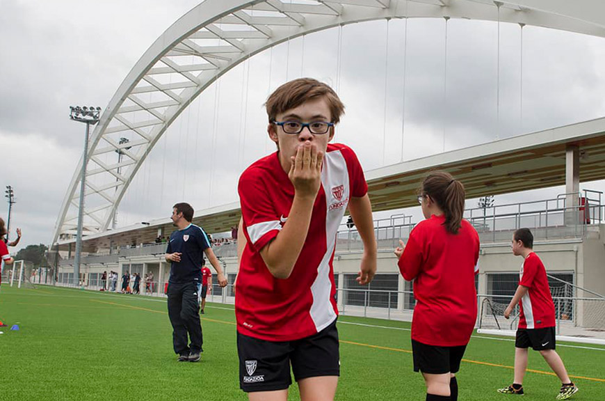 Niño con gafas deportivas participando en un proyecto de inclusión de la Fundación Athletic Club en un campo de fútbol.